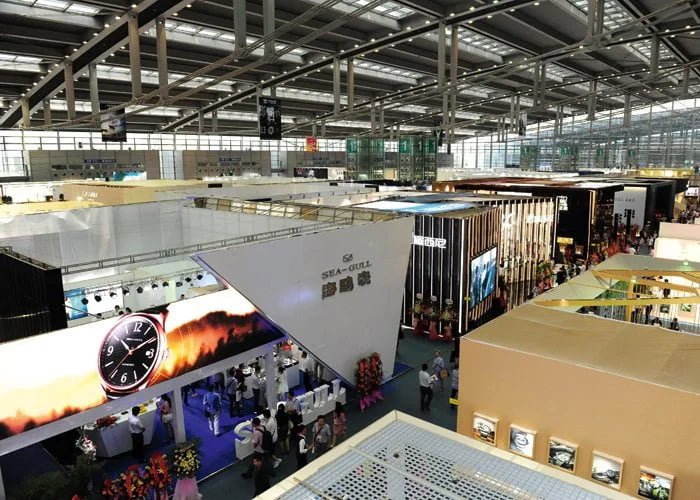 A busy watch exhibition hall with brand booths and people networking