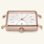 Rectangular rose gold watch case with white dial, minimalist hour markers, and crown. Close-up view of watch frame details.