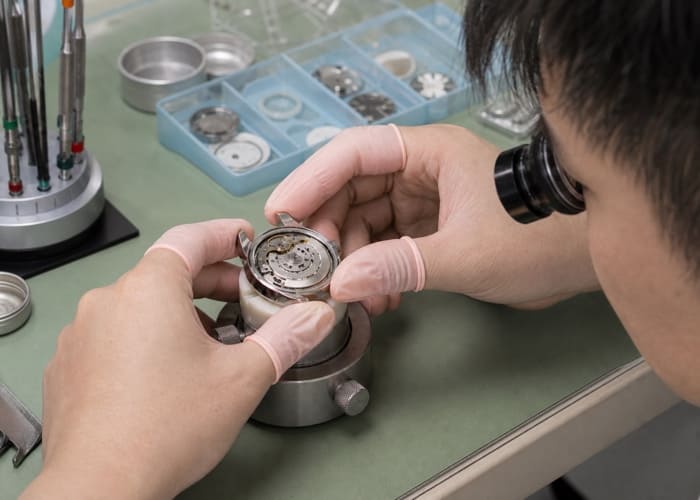 A detailed shot of a watchmaker assembling a high-quality custom watch in a clean Shenzhen factory.