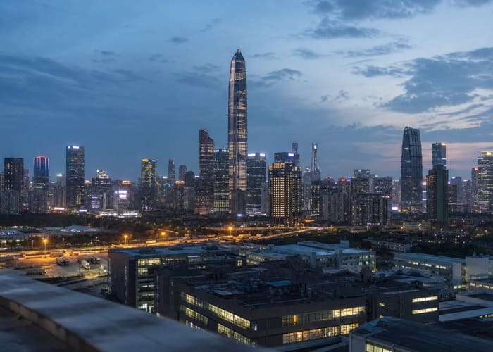 A panoramic evening view of the Shenzhen skyline, representing the global hub of Chinese watch manufacturing and technology.