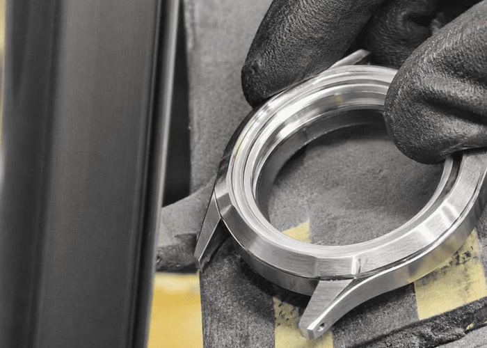 Worker hand-polishing a watch case with mixed finishes